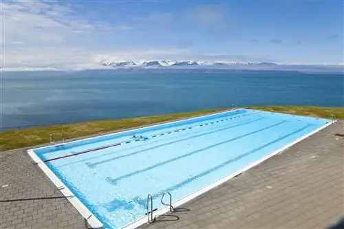 Ярко-синий бассейн на берегу моря, создающий атмосферу пейзажного бассейна.