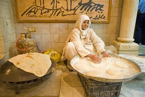 Женщина лепит лепешки на традиционном подносе в ресторане Tawaheen Al Hawa. Амман, Иордания