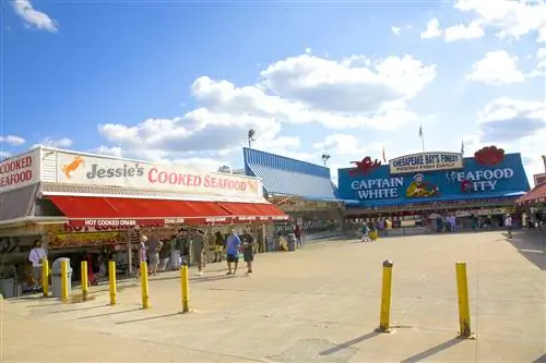 Люди выходят на муниципальный рыбный рынок в The Wharf в Вашингтоне, округ Колумбия. На заднем плане - экстерьеры ресторанов Jessie's Cooked Seafood и Captain White Seafood City.