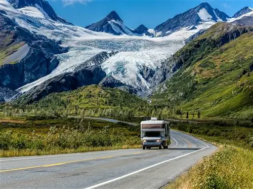 Дом на колесах едет по шоссе Ричардсон на Аляске на фоне ледника и гор.
