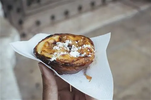 Рука держит традиционный португальский пирог из Pasteis de Belem в Лиссабоне, Португалия.