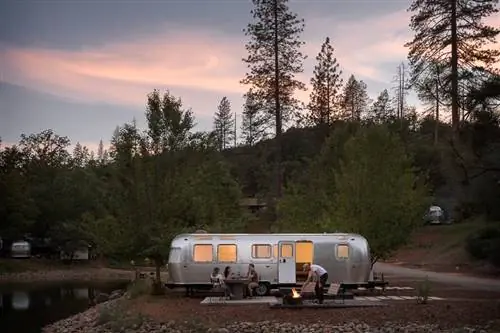 Люди за пределами Airstream на площадке для глэмпинга у костра