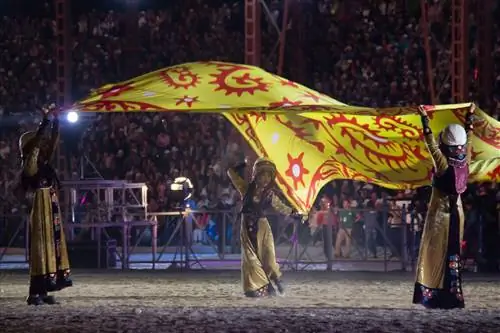 Кыргызские танцоры кружатся с гигантским желтым флагом на переполненном стадионе на церемонии открытия Всемирных игр кочевников 2014 года.