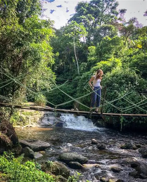 Женщина стоит на мосту через ручей в Бразилии