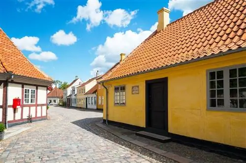 Место рождения Ганса Христиана Андерсена - одноэтажный традиционный дом с желтыми внешними стенами и крутой крышей из терракотовой черепицы; улица снаружи мощеная