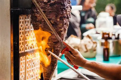 Срезание мяса с вертелов для приготовления Tacos Al Pastor в Мексике