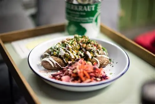 Оловянное блюдо, полное картофеля, салата из красной капусты и фасоли, сбрызнутой белой заправкой.