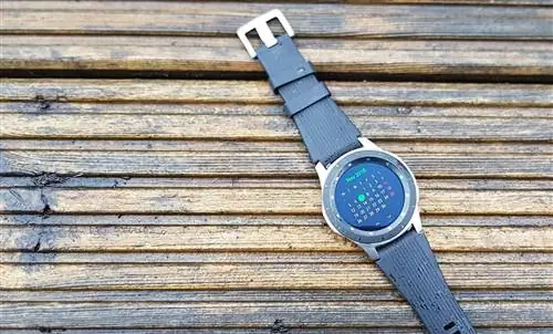 Часы Samsung Galaxy Watch с календарем на циферблате и черным ремешком.