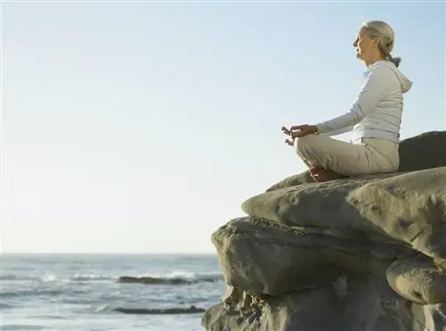 Женщина выступает посредником на скале с видом на Тихий океан недалеко от Сан-Диего.