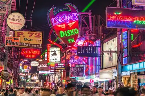 Разноцветные неоновые вывески в центре Walking Street в Паттайе. Толпы людей ходят по узким улочкам с барами и ресторанами.
