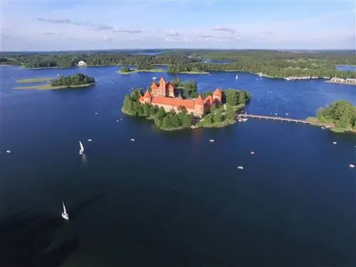 Вид с воздуха на Тракайский островной замок с небольшими лодками, плывущими по окружающему озеру.