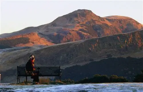 Мужчина смотрит на Холлируд-парк и место Артура с Калтон-Хилл со снегом