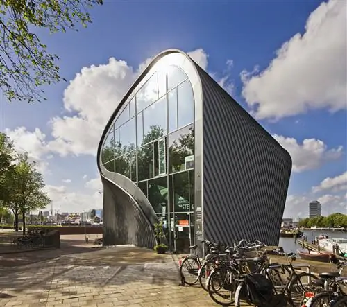 Современное изогнутое здание из стекла и стали на краю причала.