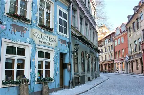 Вид на красочные фасады зданий красивой улицы Яуниела в Риге, которая представляет собой извилистую мощеную улочку.