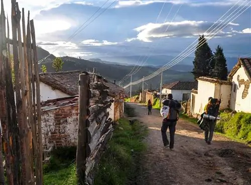 Путешественники с рюкзаками идут по грунтовой дороге в Монгуи