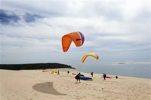 Параплан готовится взлететь с вершины песчаной дюны