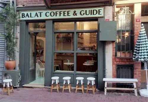 Ряд деревянных табуретов, выкрашенных белой краской, стоят возле Balat Coffee & Guide, который поддерживает местные сообщества.