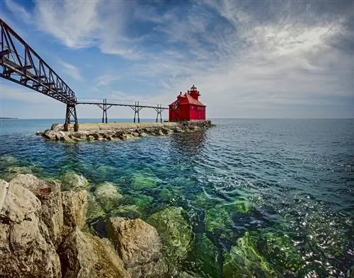 маленький красный маяк сидит в чистых голубых водах озера мичиган