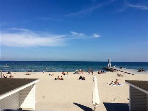 Люди отдыхают на нетронутом участке белого песка с голубым океаном за его пределами.