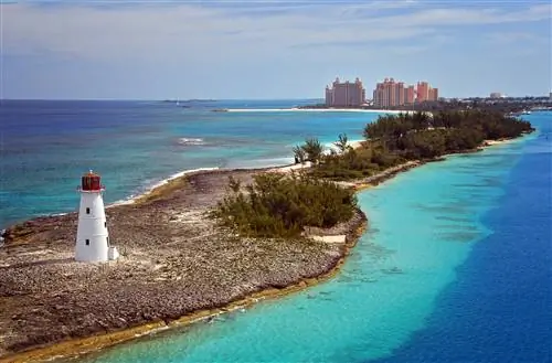 Вид с воздуха на маяк на изрезанном берегу с заросшим кустарником. Вдалеке виден курорт Атлантис.