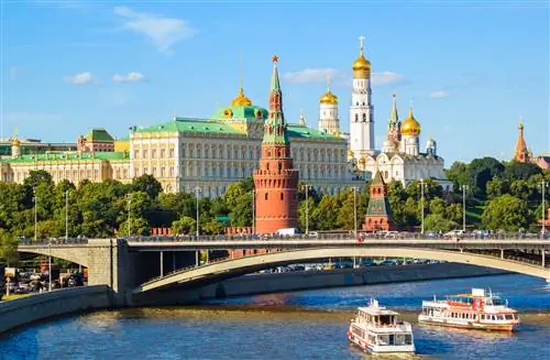Ряд больших зданий, внешнее с темно-красными стенами, расположено вдоль реки в городе.