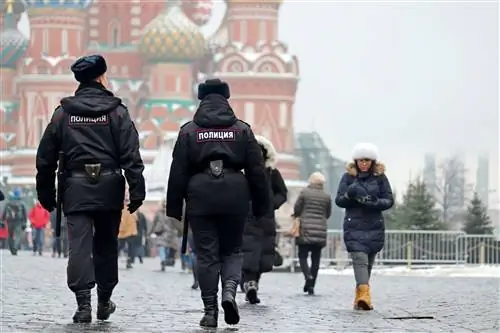 Двое полицейских, одетых в черное, идут по туристическому району.