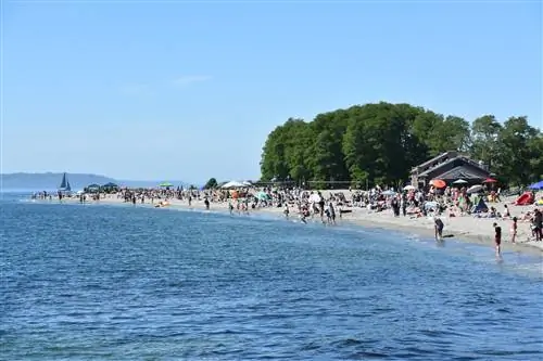 Группы людей стоят вдоль берега на пляже Golden Gardens.