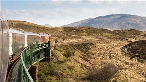 Поезд Caledonian Sleeper пересекает виадук Раннох на живописной железной дороге West Highland Line в Шотландском нагорье; изображение взято с поезда на повороте, поэтому вы видите поезд, выгибающийся вперед через бесплодный участок холмистой местности.. Поезд Caledonian Sleeper пересекает виадук Раннох на живописной железной дороге West Highland Line в Шотландском нагорье; изображение взято с поезда на повороте, поэтому вы видите поезд, выгибающийся вперед через бесплодный участок холмистой местности..