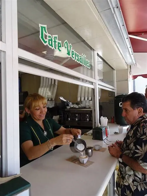 Женщина подает кофе клиенту в La Ventanita в Café Versailles, Майами Женщина подает кофе клиенту в La Ventanita в Café Versailles, Майами