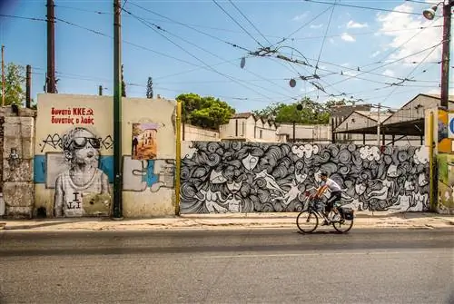 Мужчина едет на велосипеде мимо красочных граффити в центре Афин.