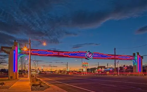 Неоновая вывеска Route 66 над Central Ave., (Route 66) Альбукерке, Нью-Мексико, смотрит на запад на закате. Его также называли шоссе Уилла Роджерса.
