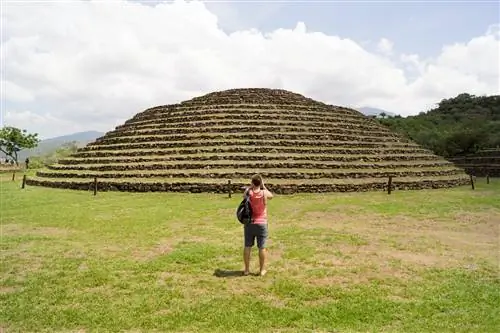 Турист смотрит на руины Гуачимонтонес, пирамидальную структуру, покрытую зеленым мхом.