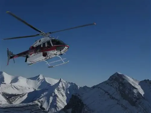 Зимой вертолет парит над заснеженными горами в Банфе и Лейк-Луизе.