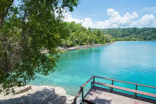 Бирюзовая вода окружена кирпичными строениями, скалами и зелеными деревьями на пляже Джеймса Бонда.