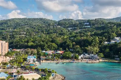 Вид с корабля на голубые воды Рыбацкого пляжа в Очо-Риос, Ямайка. На пляже большие группы людей, в океане большие надувные сооружения, а на мелководье пришвартован парусник.