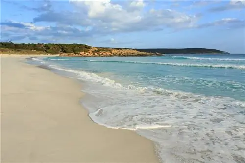 Волны плещутся о светло-коричневый берег залива Бремер в Австралии.