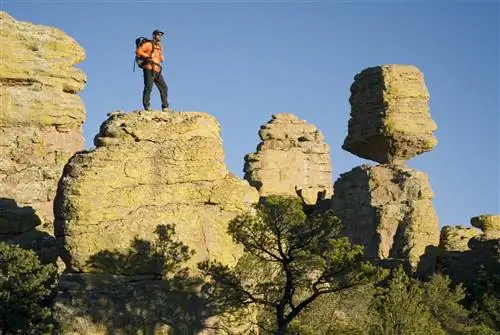 Человек стоит на скале возле Balanced Rock; большой валун, качающийся на узком постаменте