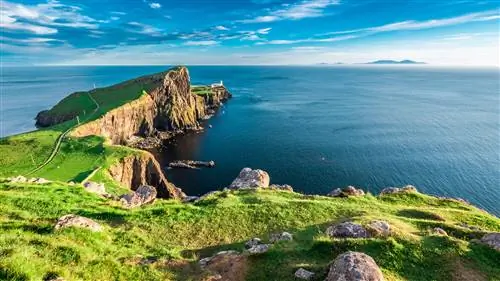 Полуостров, выступающий в море, с крошечным белым маяком на конце. Пейзаж зеленый и совершенно пустой от людей