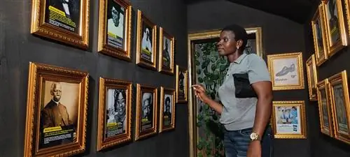 Женщина рассматривает фотографии в рамке в музее Vintage Africana.