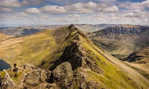 Восхождение на Striding Edge Хелвеллина, вид с вершины. Дорожка очень узкая, проходит вдоль пика с крутыми краями по обеим сторонам. На заднем плане зеленые холмы