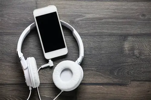 Белые наушники и смартфон на деревянном столе