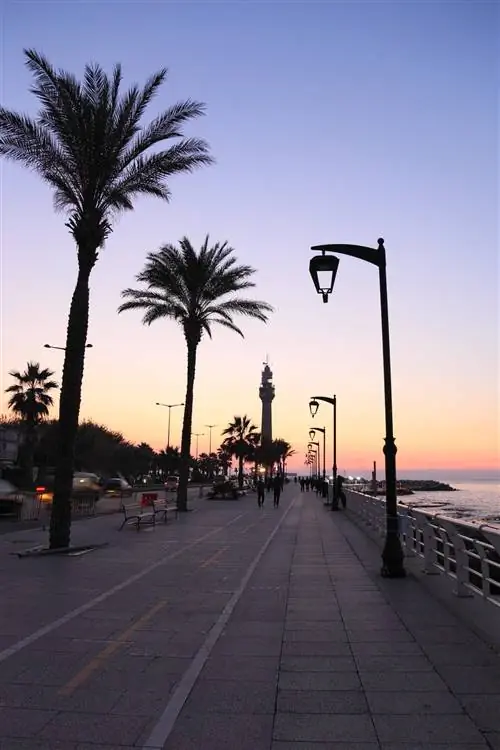 Люди гуляют по набережной Корниш в Бейруте на закате.