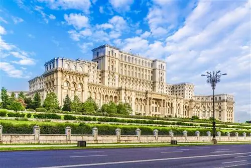 Огромное мраморное здание с несколькими ярусами и сотнями окон в ландшафтных садах.