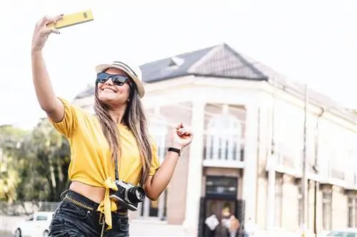 Веселая и улыбающаяся латиноамериканка-фотограф, туристка, делающая селфи на улице в Гондурасе