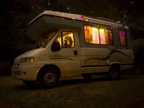 Ночное фото автофургона с собакой, выглядывающей из окна.