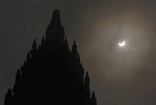 Частное солнечное затмение видно за храмом Прамбанан 9-го века в Джокьякарте, Индонезия, в среду, 9 марта 2016 года. Редкое астрономическое явление можно наблюдать в среду на узком пути, который простирается через 12 провинций, охватывающих три временных зоны и около 40 миллионов человек..