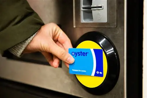 Женская рука держит синюю карту Oyster, касаясь желтой подушечки на автоматических барьерах для билетов