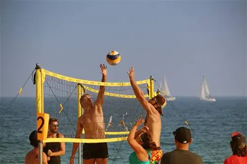 Любители пляжного отдыха играют в пляжный волейбол на пляже Богатель в Барселоне.