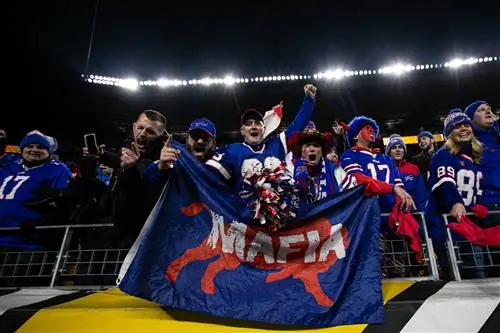 Поклонники Bills Mafia держат флаг с надписью «Мафия» и аплодируют во время футбольного матча НФЛ Поклонники Bills Mafia держат флаг с надписью «Мафия» и аплодируют во время футбольного матча НФЛ
