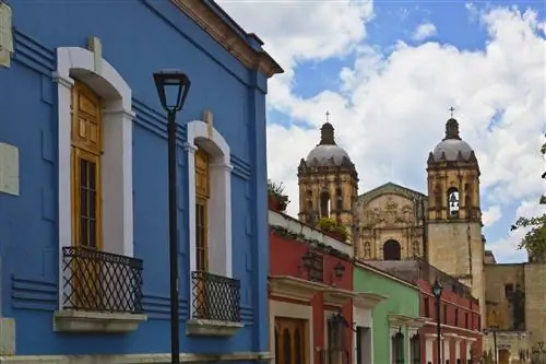 Красочно раскрашенные дома и магазины выстроились вдоль улиц перед церковью Санта-Доминго, Оахака, Мексика. (Фото: Education Images/UIG через Getty Images)